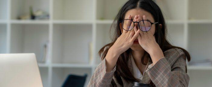 An upset woman covering her eyes on a call with her telehealth doctor.