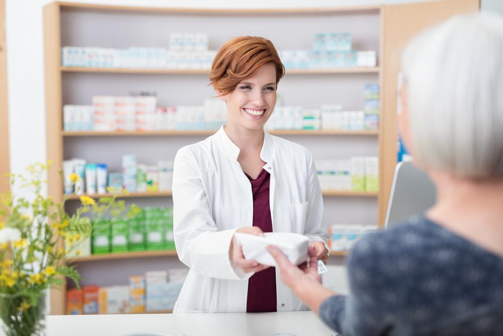 A pharmacist handing an elderly woman her prescription.