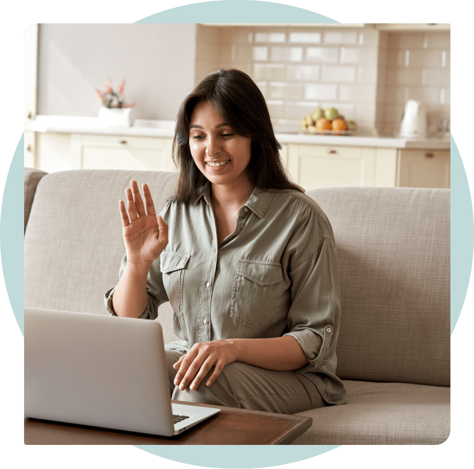 A woman smiling and waving to her telehealth doctor.