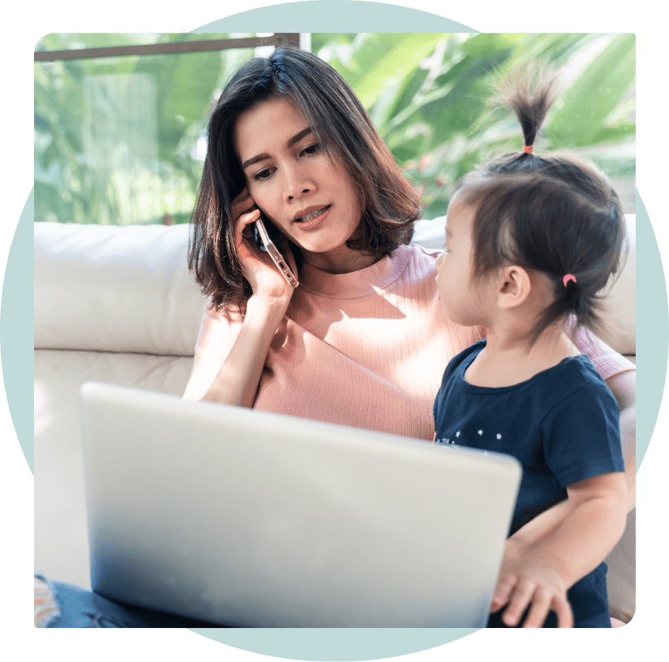 A concerned looking woman speaking on the phone while on a telehealth call with her young daughter.
