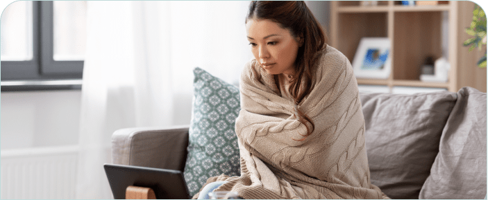 A woman wrapped in a blanket consults a telehealth doctor.