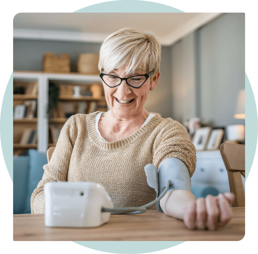 Elderly woman smiling while checking her blood pressure at home.